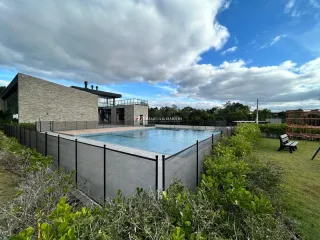 Foto externa mostrando uma piscina cercada por uma cerca e vegetação.