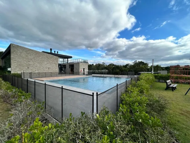 Foto externa mostrando uma piscina cercada por uma cerca e vegetação.