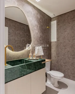 Foto de um banheiro com bancada de mármore verde e vaso sanitário branco.