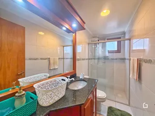 Banheiro com azulejos brancos e bancada escura.