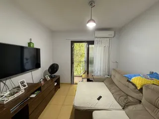 Sala de estar com sofá e televisão em um ambiente claro.