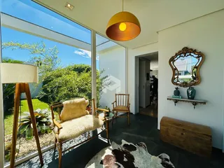 Sala de estar com grande abertura de vidro e vista para um jardim verde.