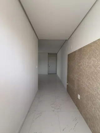 Corredor interno de uma residência com paredes brancas e piso claro.