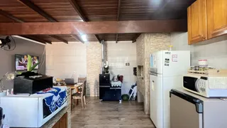 Interior de uma cozinha e sala de estar com piso de madeira e teto de madeira.