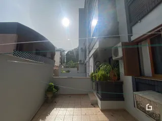 Vista externa de um pátio com piso de cerâmica e parede branca.