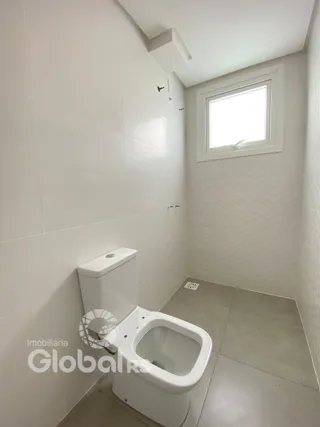 Foto interna de um banheiro com revestimento branco.