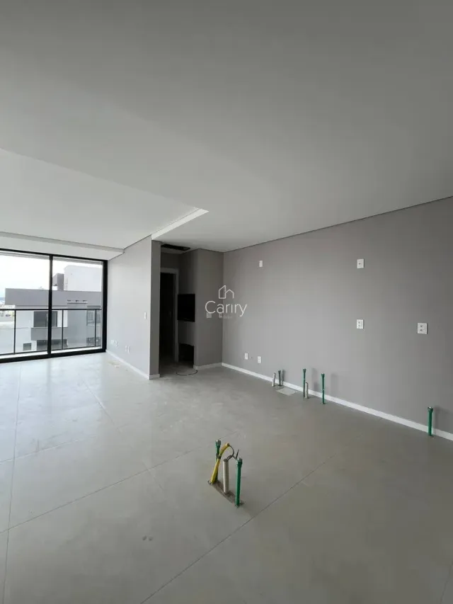 Foto de um ambiente interno vazio com piso de concreto e paredes cinzas.