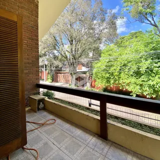 Vista da varanda com vista para a vegetação e casas ao fundo.