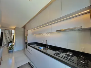 Vista da cozinha moderna com armários brancos e bancada escura.