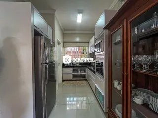 Foto interna da cozinha mostrando armários e eletrodomésticos de aço inoxidável.
