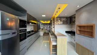 Cozinha moderna com armários brancos e piso claro.