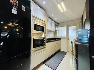Interior de uma cozinha moderna com armários brancos e eletrodomésticos pretos.