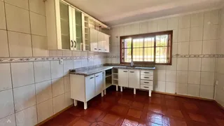 Cozinha com armários brancos e piso de madeira.