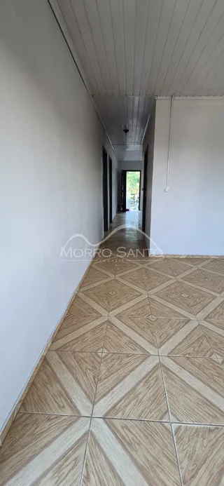 Corredor interno com piso de ladrilhos claros e teto de painel.