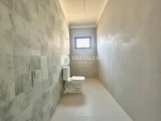 Corredor interno com revestimento de cerâmica e vaso sanitário.