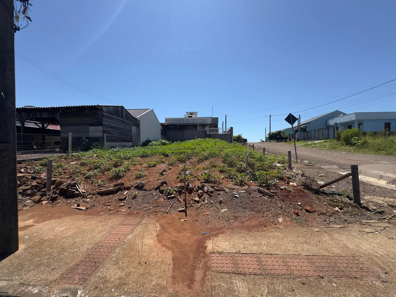 Vista externa da propriedade mostrando terra e vegetação rasteira.
