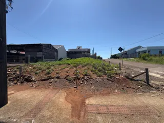 Vista externa da propriedade mostrando terra e vegetação rasteira.