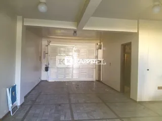 Foto do interior de uma garagem com porta de correr branca e piso de ladrilhos.
