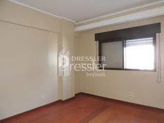Vista interna de um corredor com paredes claras e piso de madeira.