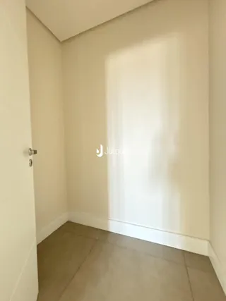 Vista interna de um corredor com paredes brancas e piso claro.