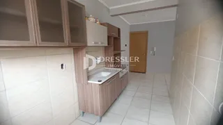 Vista interna de uma cozinha com armários e revestimento de cerâmica.