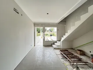 Hall de entrada com escadaria e vista para o exterior da residência.