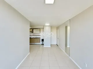 Hall de uma residência com piso de cerâmica clara e paredes brancas.