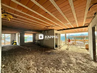 Foto de uma estrutura em construção com vigas expostas e solo de terra.