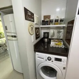 Foto de uma área de cozinha com máquina de lavar roupa e armários brancos.