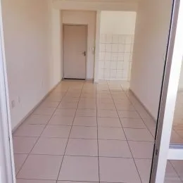 Corredor interno com piso de cerâmica clara e paredes brancas.