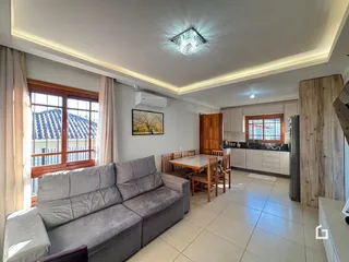 Sala de estar com sofá e janelas grandes em uma residência.