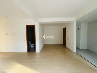 Um corredor interno com piso de madeira clara e paredes brancas.