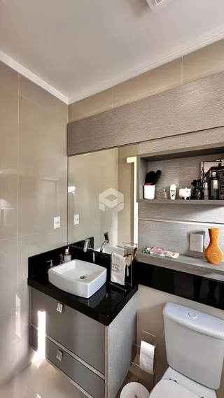 Foto de um banheiro moderno com bancada escura e revestimento claro.