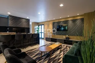Sala de estar com sofá e televisão montada na parede em um imóvel.