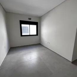 Foto de um cômodo interno com paredes claras e uma janela grande.