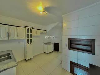 Cozinha com armários brancos e piso claro em imóvel no Brasil.