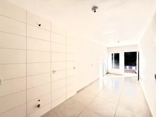 Hall de entrada com paredes brancas e piso claro.