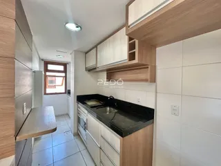 Vista interna de uma cozinha com armários e bancada escura.
