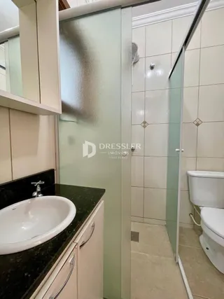 Vista de um banheiro com pia e divisória de vidro em uma propriedade.