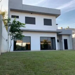 Foto da fachada de uma residência branca com gramado verde.