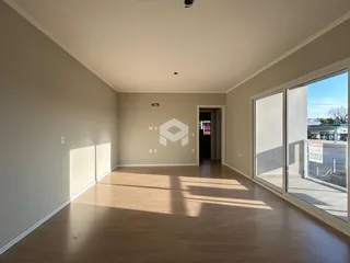 Ambiente interno de uma sala com piso de madeira clara e grande janela.
