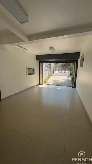 Um corredor interno com piso de porcelanato claro e acesso a uma área externa.