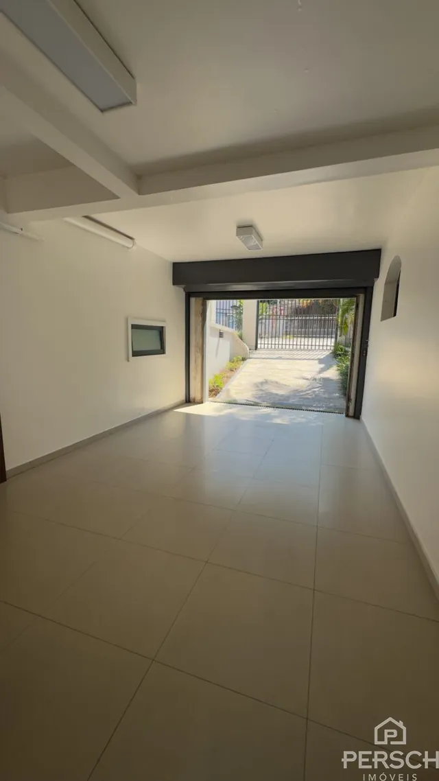 Um corredor interno com piso de porcelanato claro e acesso a uma área externa.
