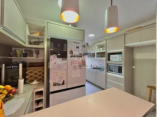 Cozinha moderna com armários brancos e eletrodomésticos em aço inoxidável.