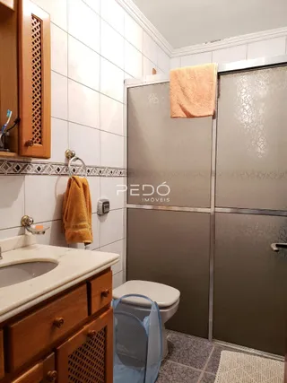 Foto de um banheiro com bancada de madeira e azulejos brancos.