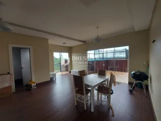 Sala de jantar com piso de madeira e portas de vidro que dão acesso ao exterior.