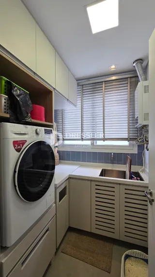 Interior de uma cozinha com armários brancos e máquina de lavar roupa.