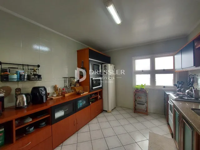 Foto interna de uma cozinha com armários de madeira e piso cerâmico.