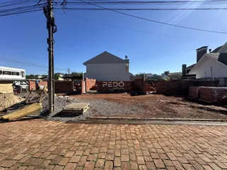 Vista externa de um terreno em Lajeado, Brasil, com muro de tijolos e área de terra.