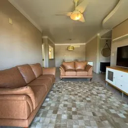 Foto de uma sala de estar com sofá marrom e piso de ladrilho claro.